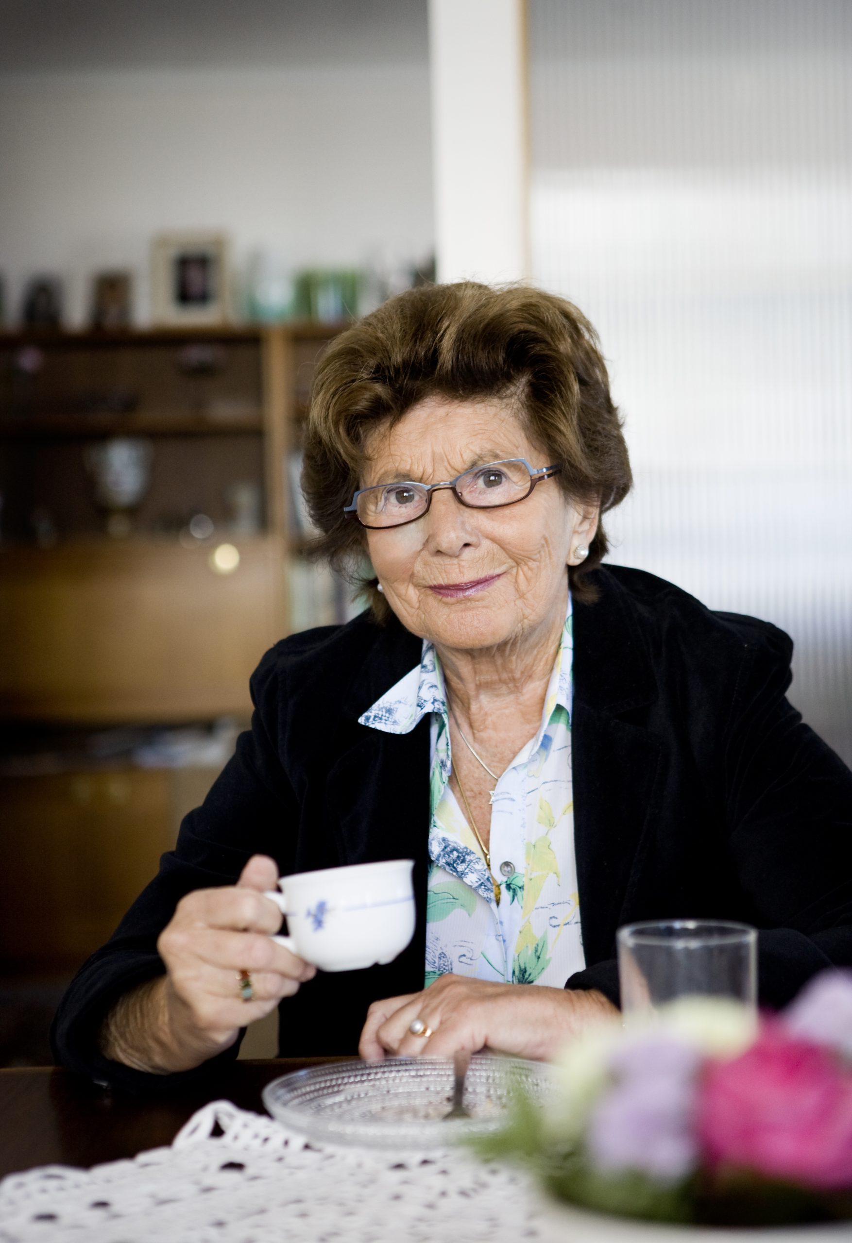 Porträtt på äldre kvinna i glasögon.