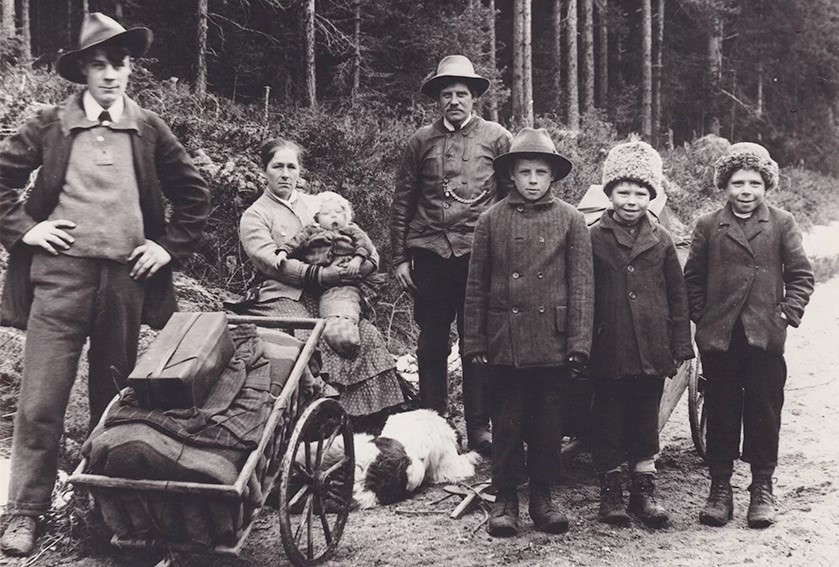 Svartvitt foto som visar en familj på en landsväg med en dragkärra.