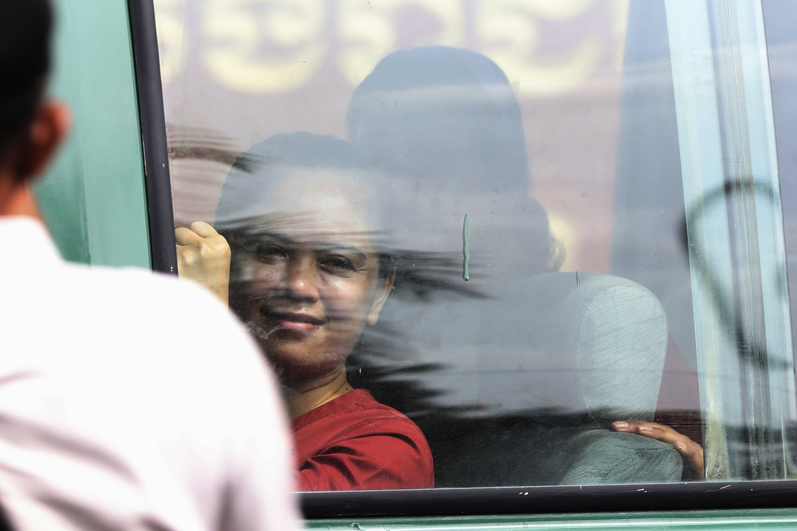 Sithar Chhim´s smiling face is seen through the window of the prison van that is bringng her from Phnom Penh Municipal Court, which has just sentenced to two years in prison.