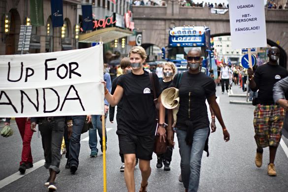 Människor i demonstrationståg bär på en banderoll med text där man kan anda att det står "for Uganda".